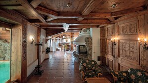 A wooden interior with a fireplace, a sofa, and a staircase leading to another room.