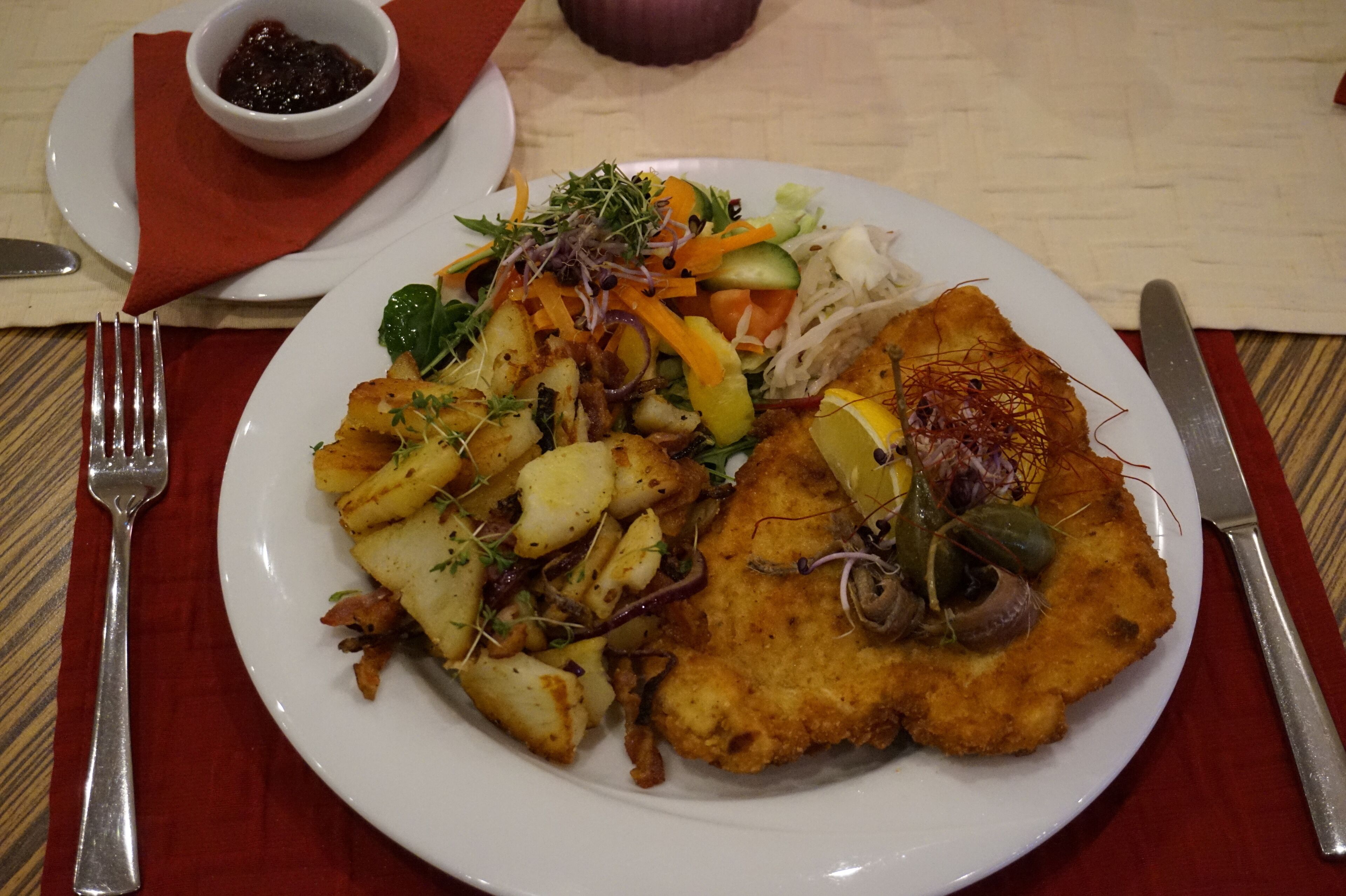 A plate of food with a fried cutlet, potatoes, and a salad.