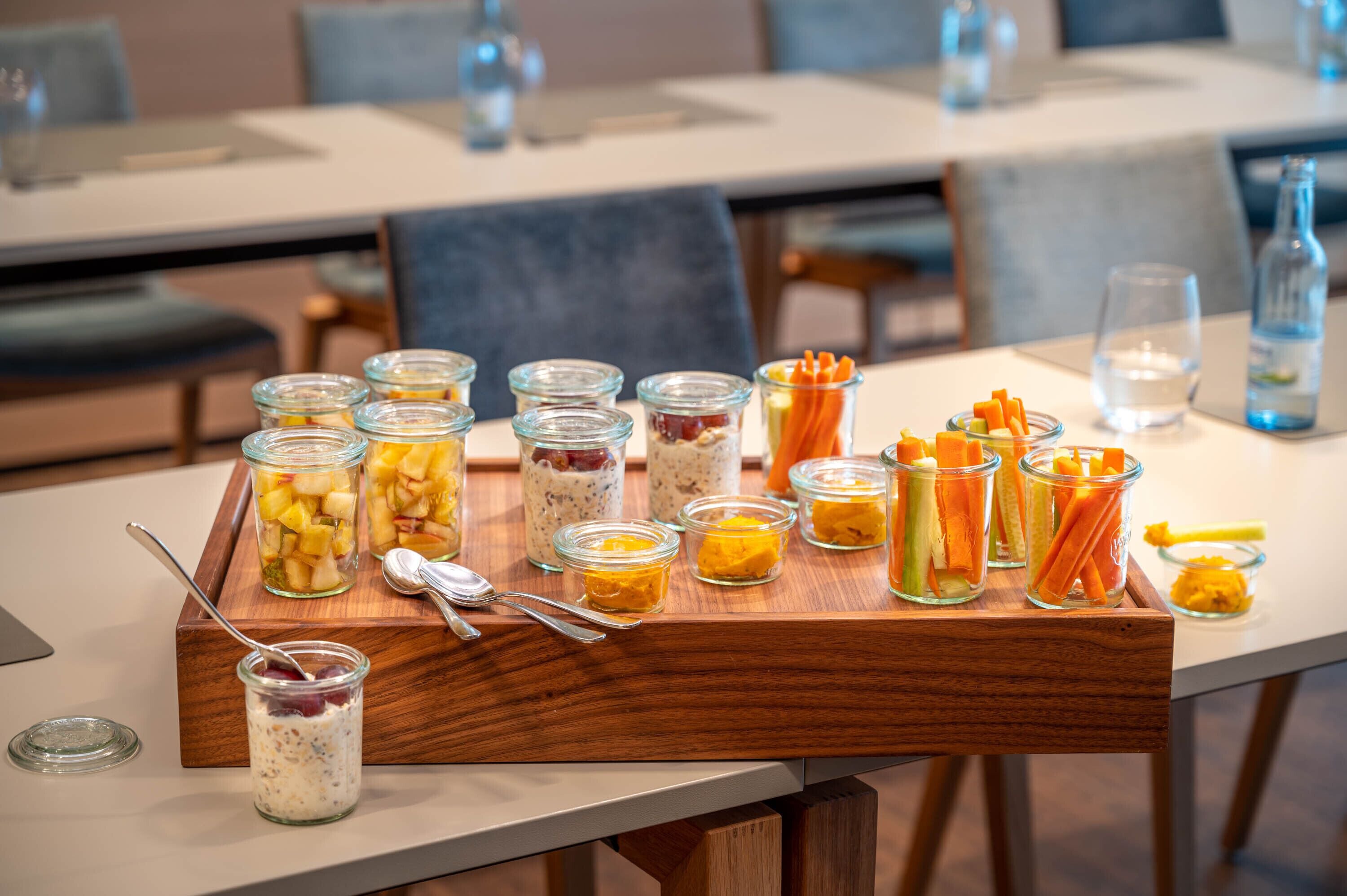 Une table de buffet présentant divers aliments dans des récipients en verre, notamment des fruits, des légumes et un yaourt en couches.