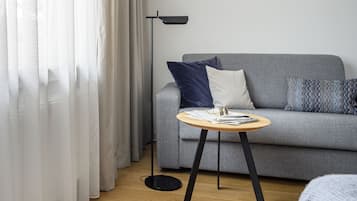 A modern living room with a grey sofa, a round wooden side table, and a black floor lamp.