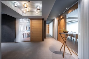 A modern interior with a wooden door, a dining area with a table and chairs, and a large window with curtains. - Hotel Maier (Friedrichshafen)