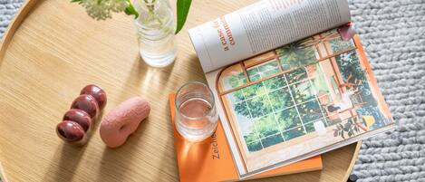 Ein Holztablett mit einem Buch, einem Glas Wasser, einer Vase mit Blumen und ein paar dekorativen Steinen.