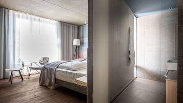 Una camera d'albergo moderna con un letto, una scrivania, una sedia, una lampada e vista sull'esterno.