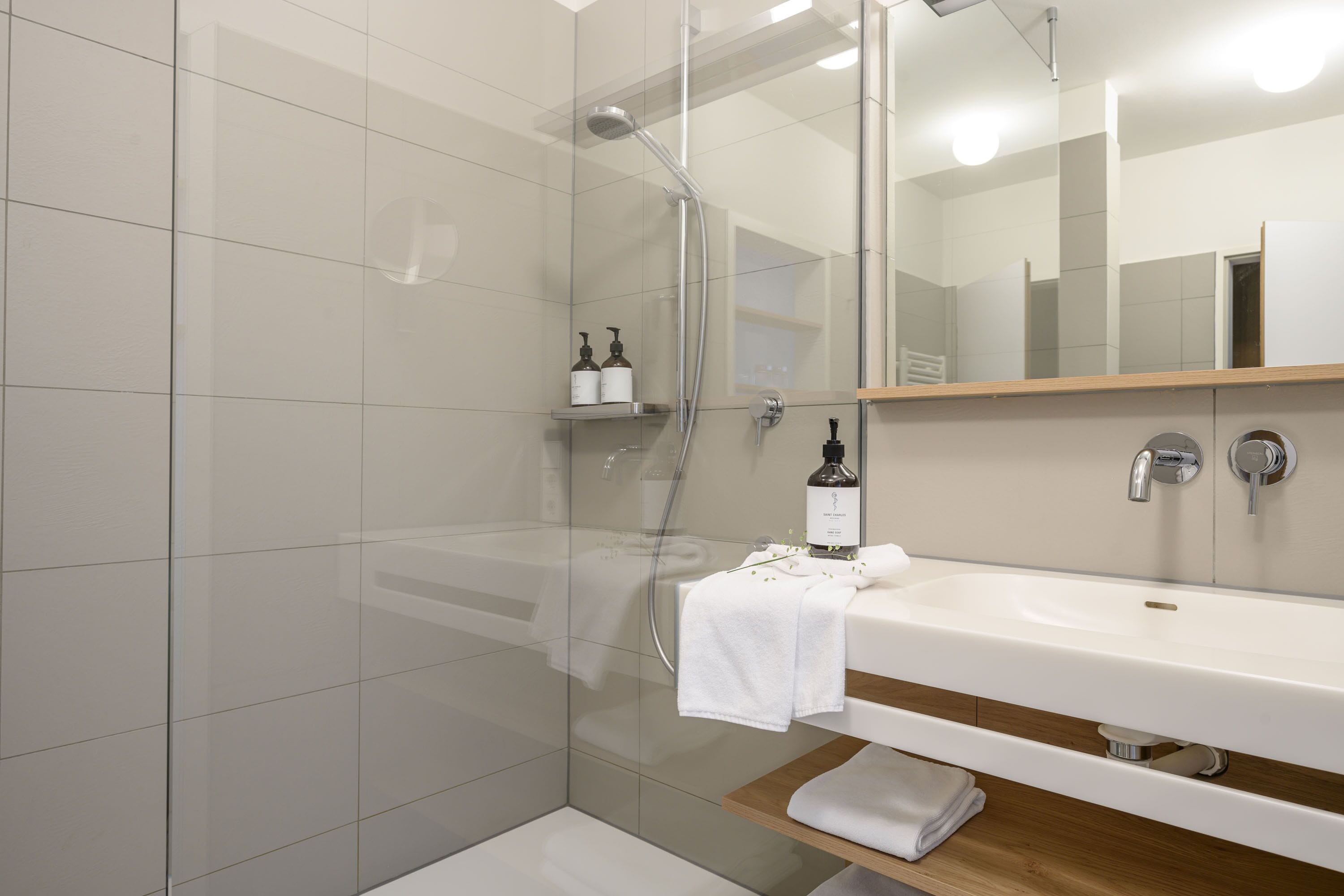 A modern bathroom with a glass-enclosed shower, a white sink, and a mirror above it.