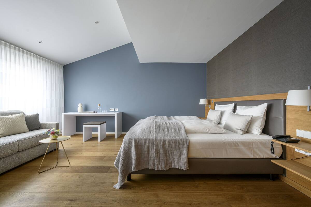 A modern bedroom with a bed, bedside table, and a desk with a chair.