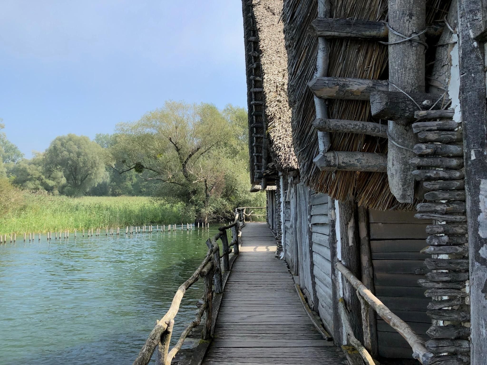 A wooden bridge leading to a traditional building with a thatched roof.