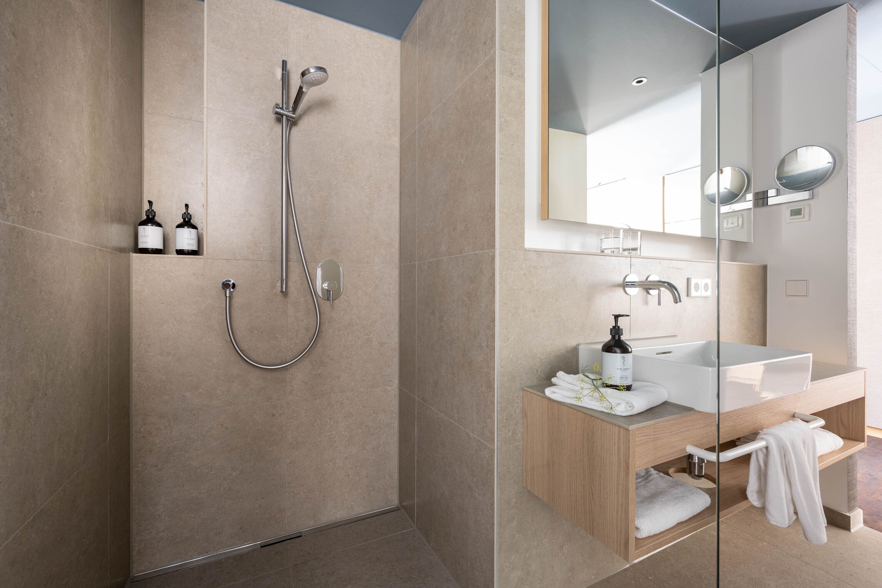 Un baño moderno con ducha de vidrio, un lavamanos blanco y un espejo grande.
