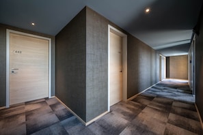 A hallway with two doors, each marked with a number. The floor has a checkered pattern. - Hotel Maier (Friedrichshafen)