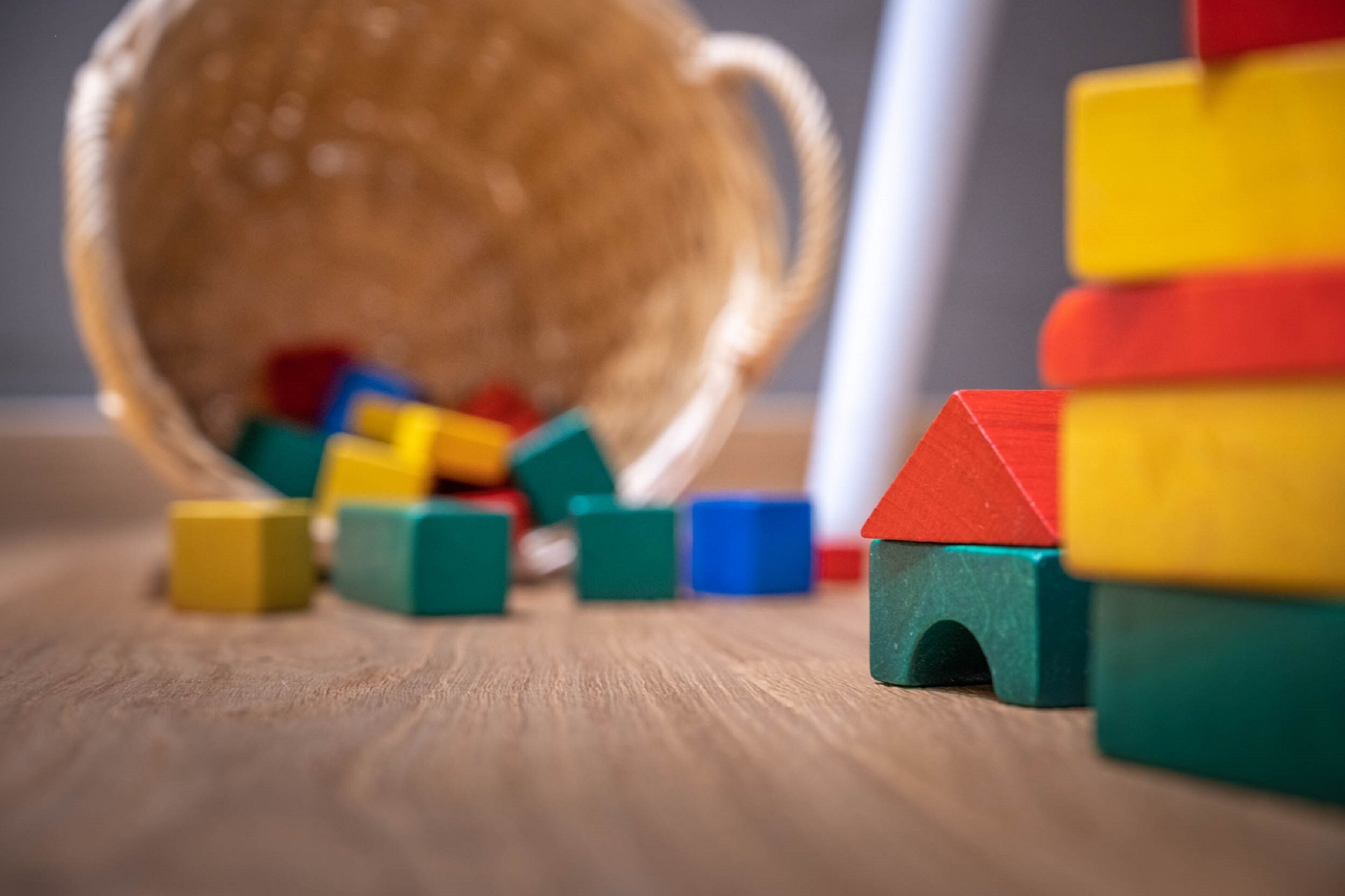 Una superficie de madera con bloques de construcción coloridos y una cesta de mimbre.