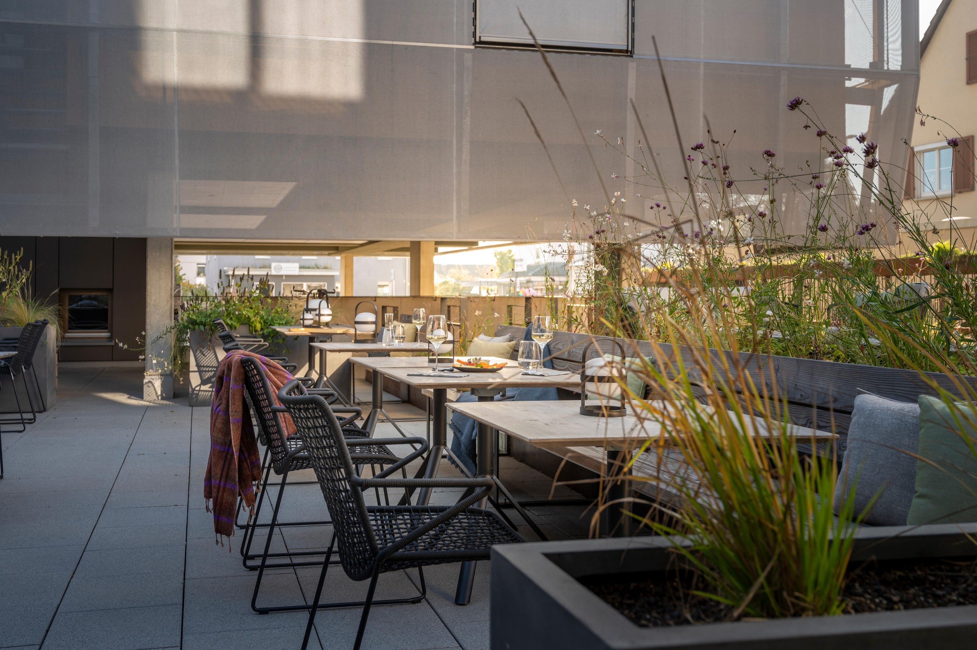 Un espace extérieur aménagé avec des tables et des chaises, entouré de plantes et de fleurs.