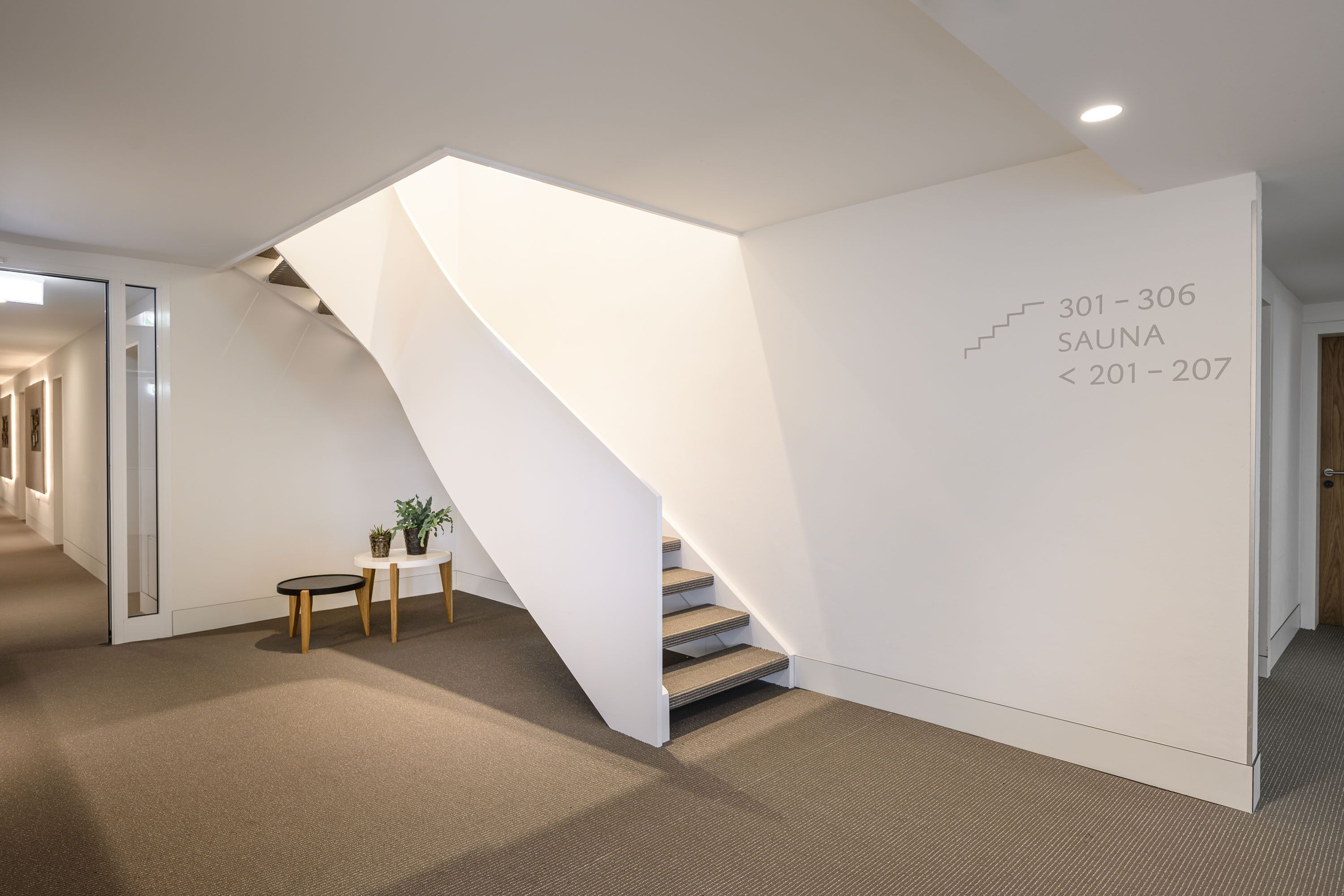 A modern interior with a staircase leading to a sauna area, marked with numbers 301-306 and 201-207.