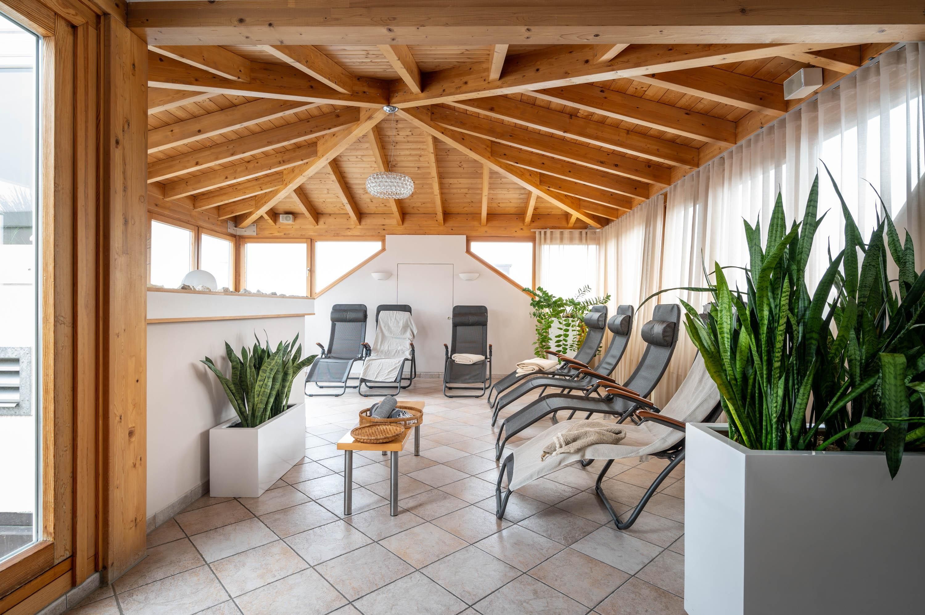A sunroom with a sloped ceiling, multiple seating areas, and large windows.