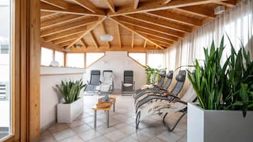 A sunroom with a sloped ceiling, multiple seating areas, and large windows.