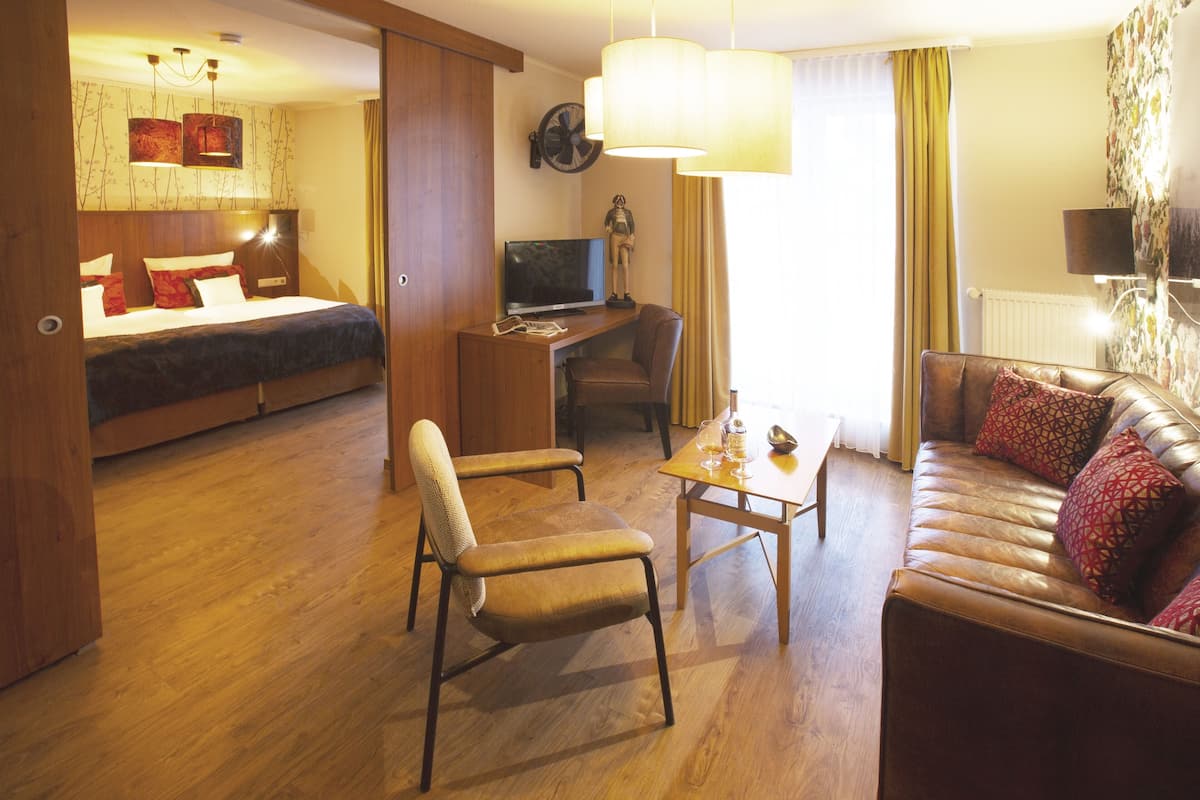 A hotel room with a bed, a desk with a computer, a sofa, and a chair.