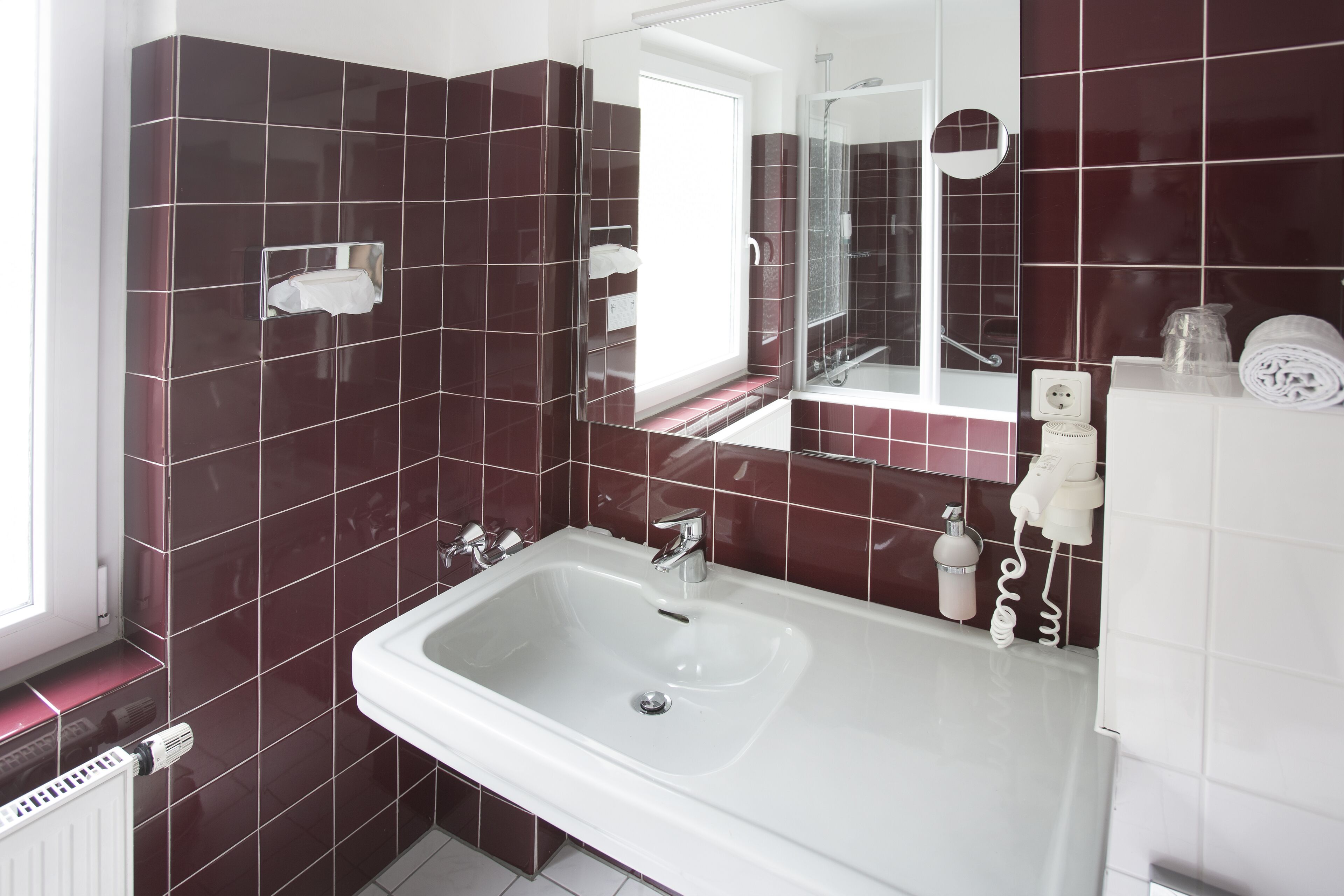 Une salle de bain avec un lavabo blanc, un miroir et une cabine de douche en verre.