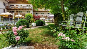 Een hotel binnenplaats met een zwembad, buiten zitplaatsen en een tuin met roze rozen.
