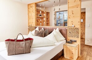 Quarto de hotel com cama, cabeceira de madeira, mesa de cabeceira com abajur e um espelho grande.