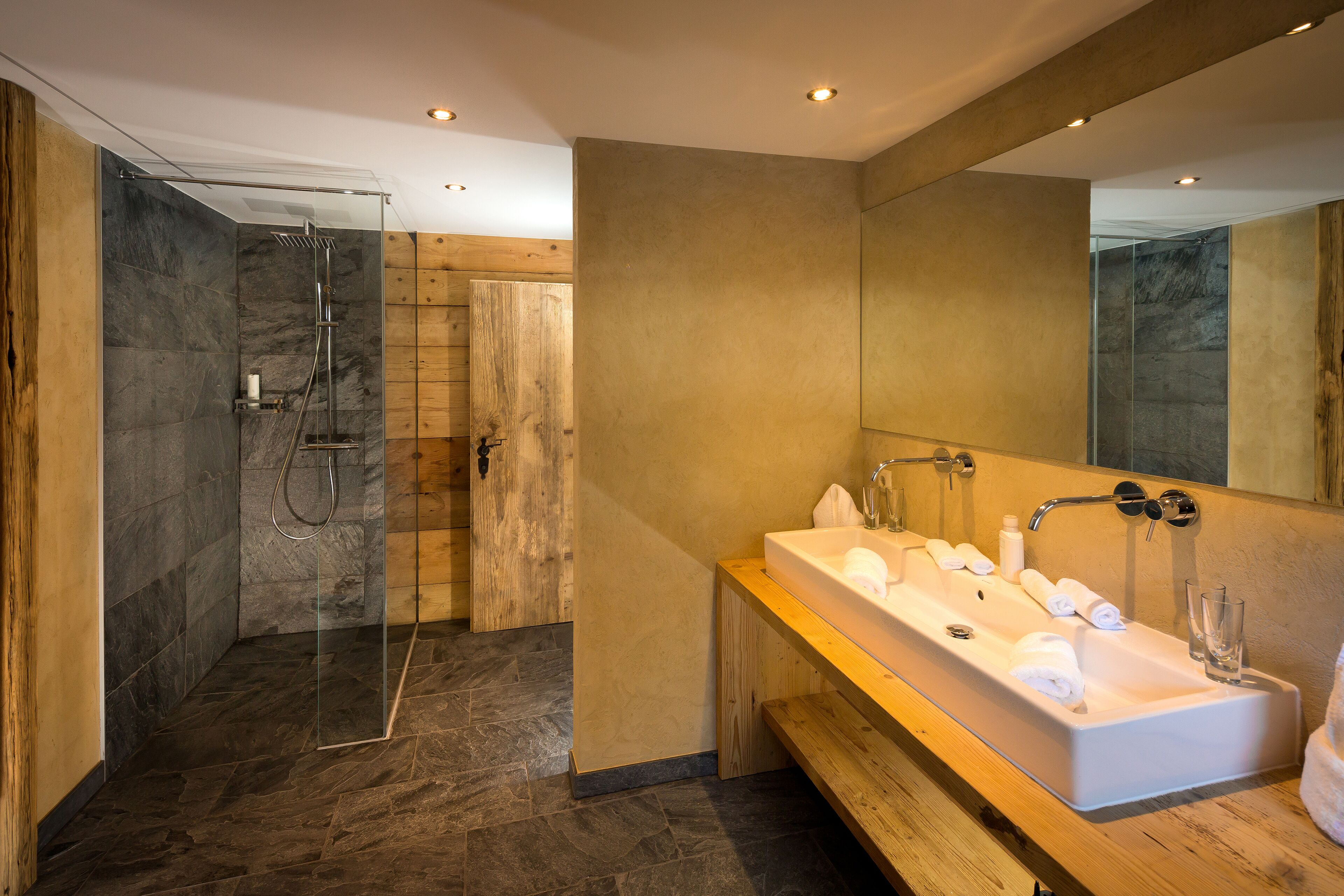 A modern bathroom with a large sink, mirror, and shower.