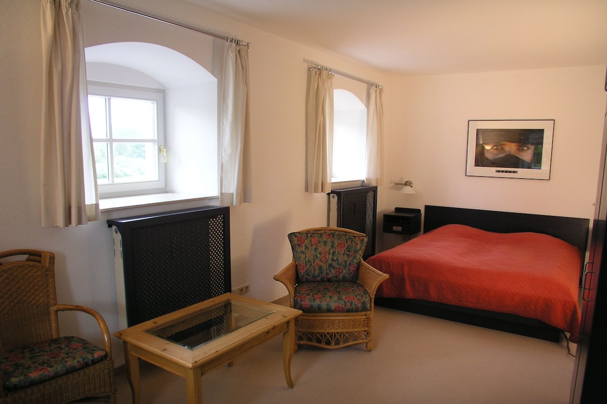 Ein Schlafzimmer mit Bett, Stuhl, Tisch und Heizkörper.