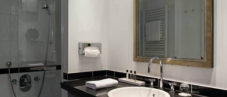 A modern bathroom with a glass-enclosed shower, a white sink, and a large mirror.