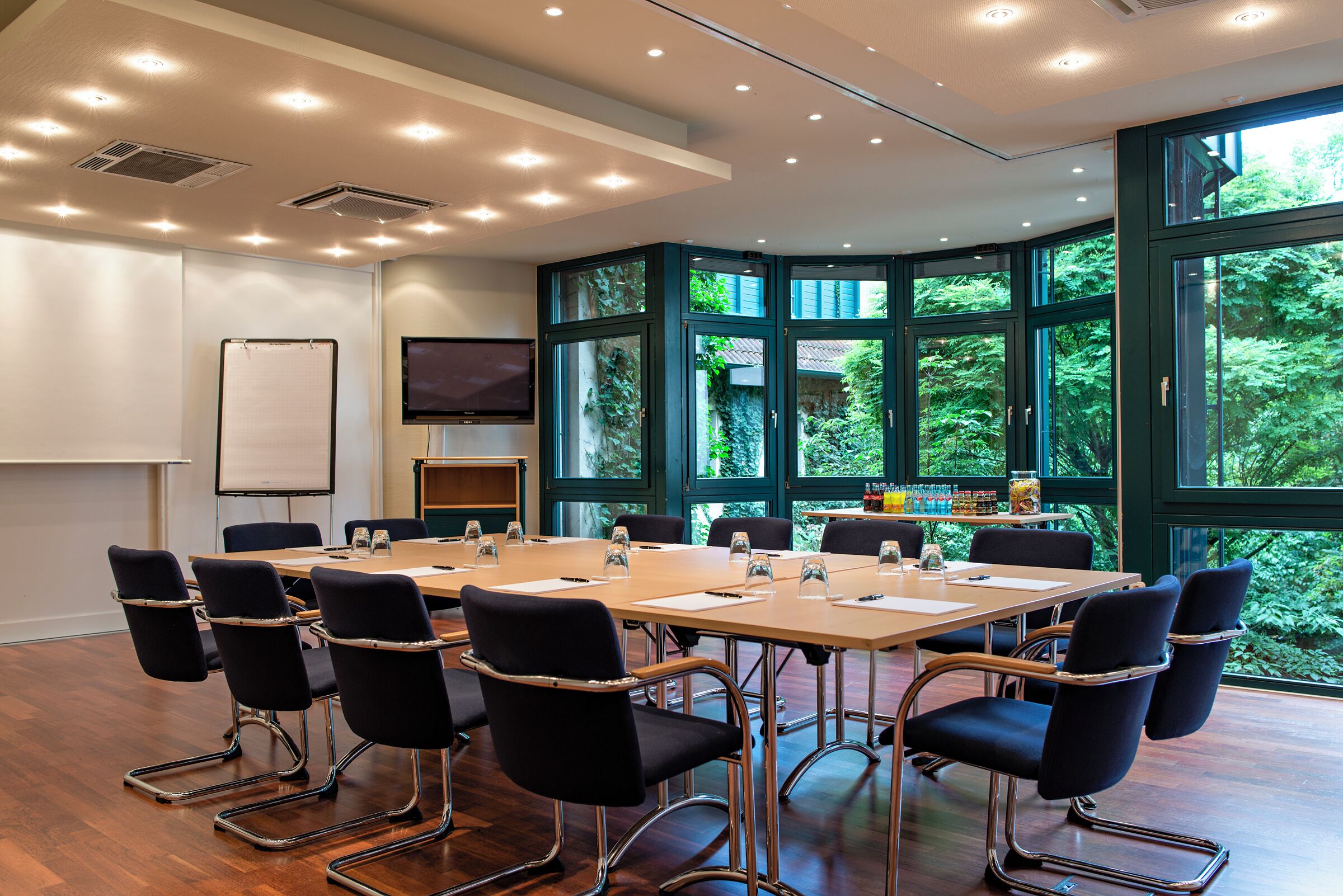 A conference room with a large table, chairs, a whiteboard, and a television.