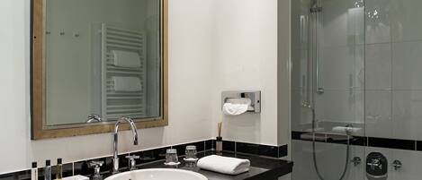 Un baño moderno con un lavabo blanco, un espejo grande y una cabina de ducha con paredes de vidrio.