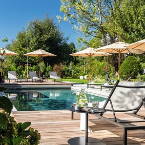 A poolside area with lounge chairs and umbrellas, a wooden deck, and a clear blue sky. - Zeller Hotel & Restaurant (Kahl)