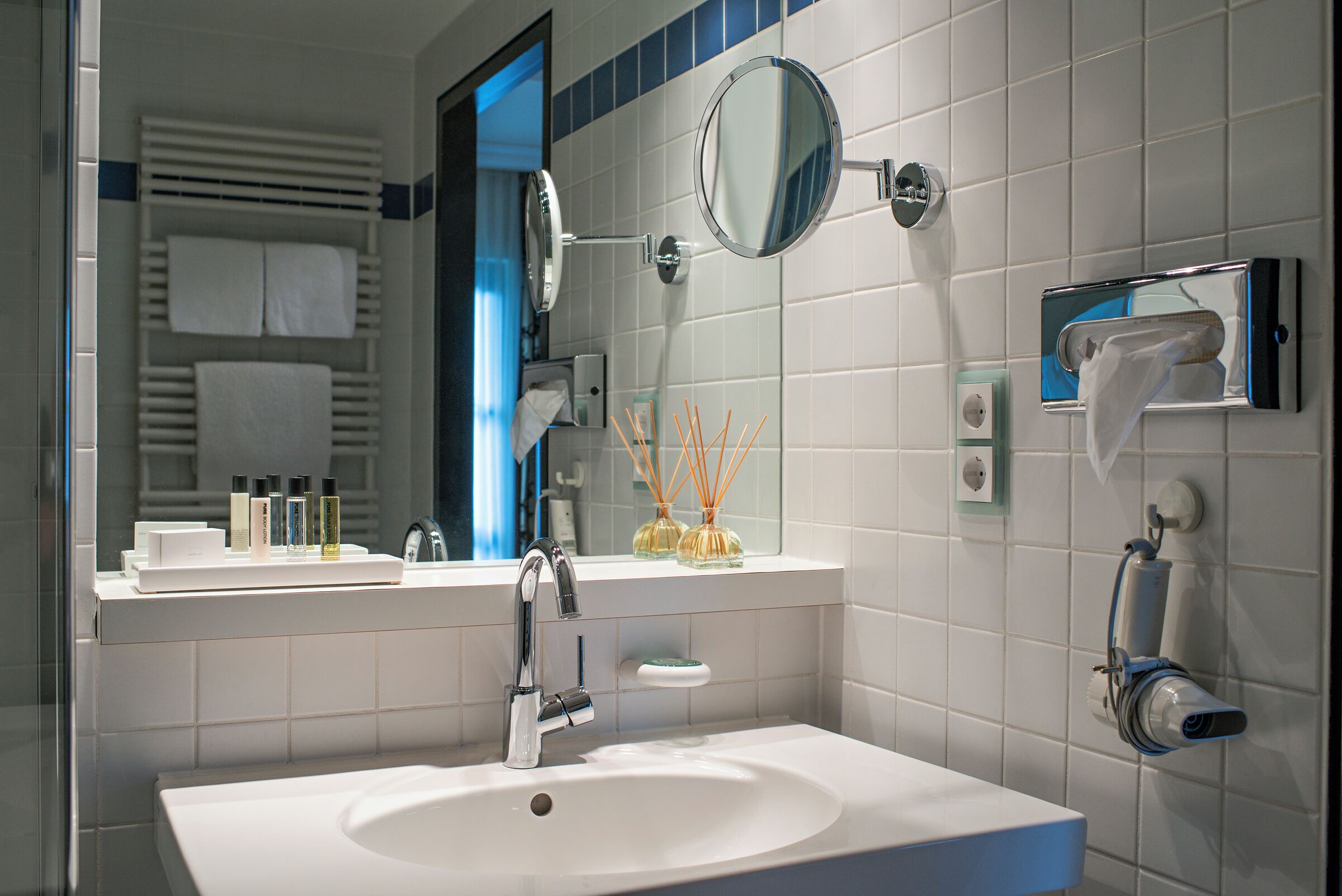 Een moderne badkamer met een witte wastafel, een spiegel en een handdoekrek.