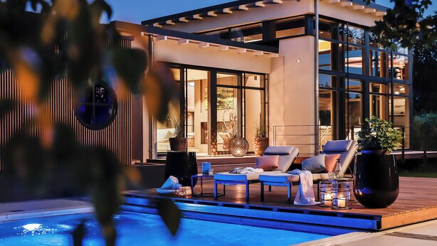 A modern outdoor pool area with lounge chairs and potted plants. - Zeller Hotel & Restaurant (Kahl)