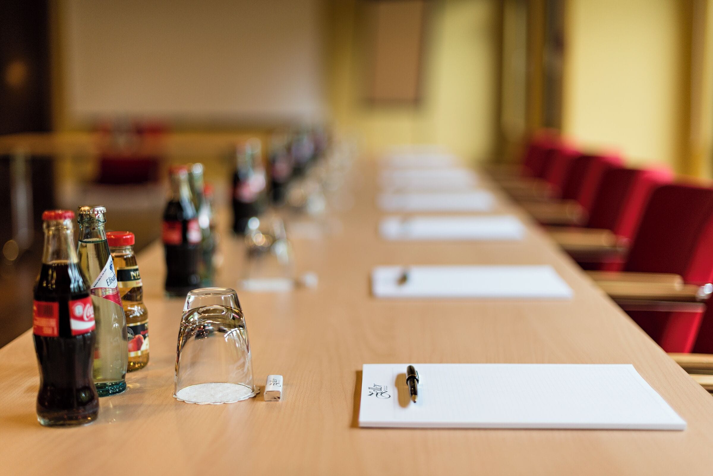 Una mesa de conferencias con botellas, vasos y un bloc de notas.
