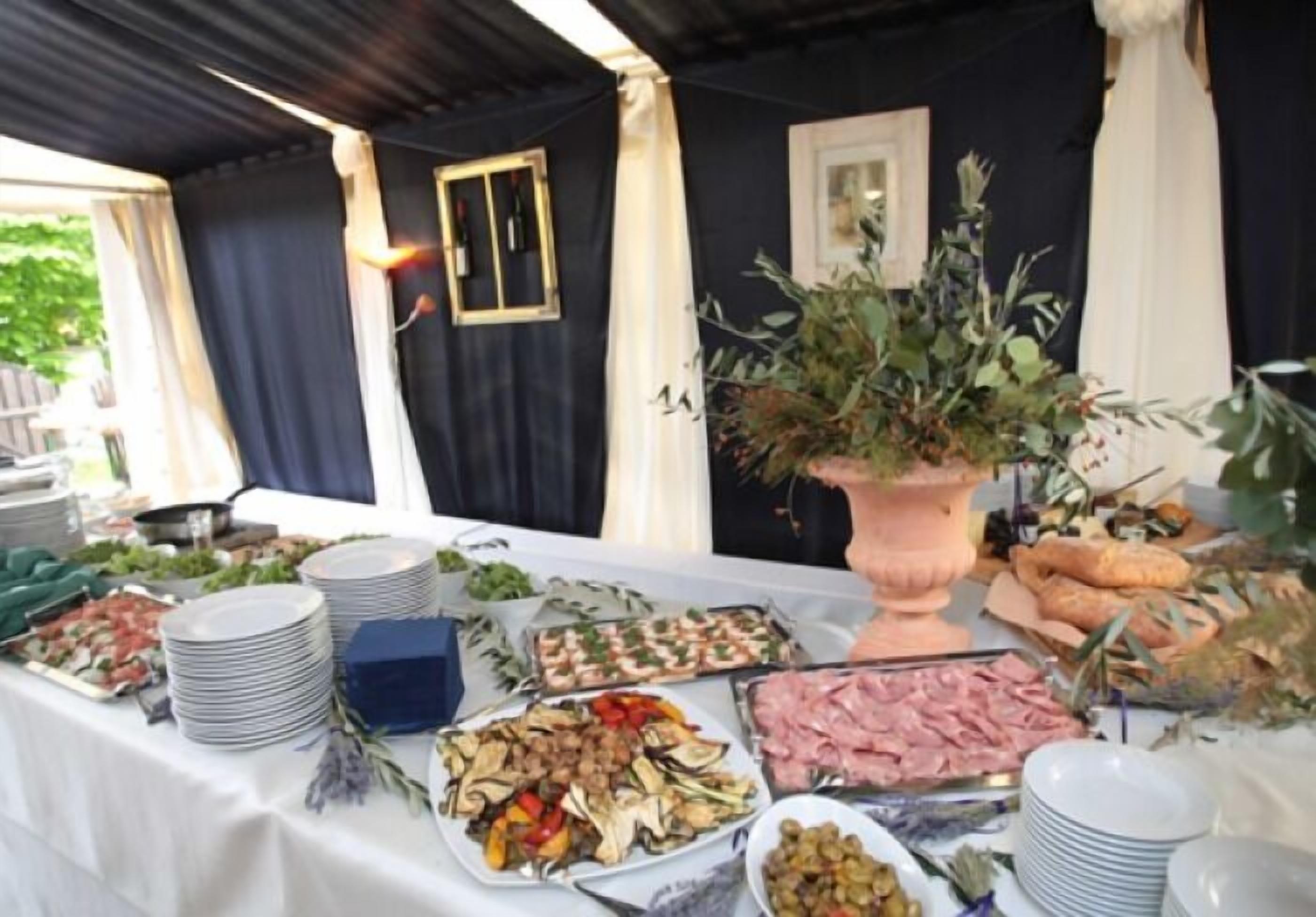 Un tavolo per buffet con diversi cibi e un grande vaso di fiori.