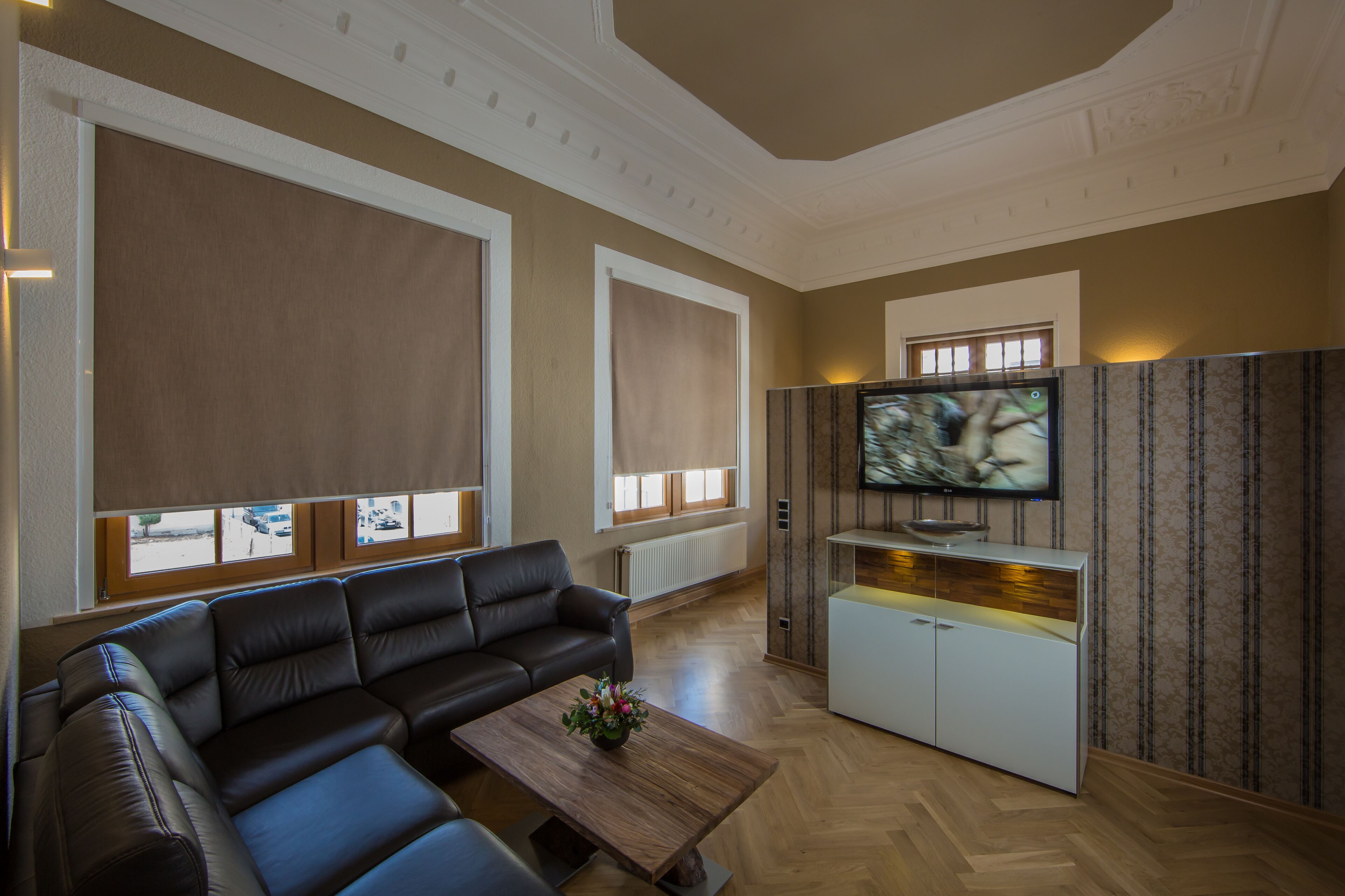 Una sala de estar moderna con un sofá de cuero, una mesa de centro, un televisor y un aparador.