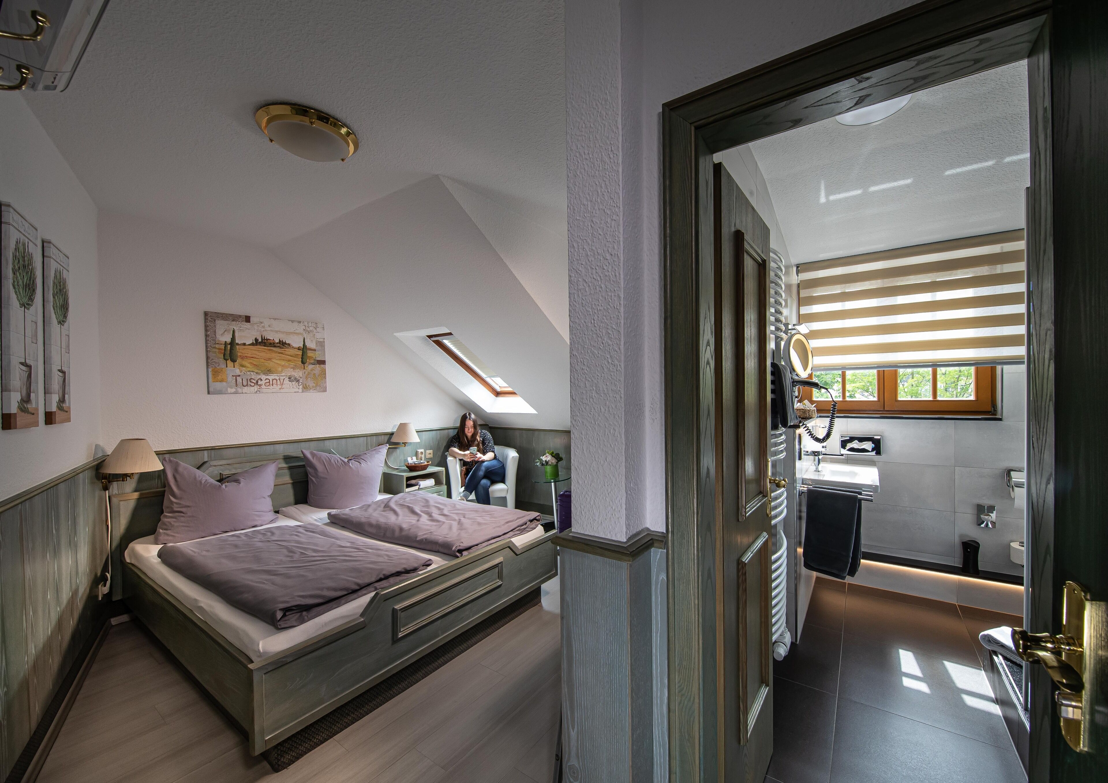 Une chambre avec un grand lit, une fenêtre de toit, une salle de bain avec fenêtre et une vue sur l’extérieur.