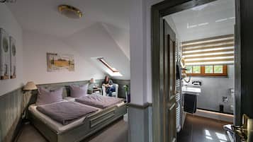 Une chambre avec un grand lit, une fenêtre de toit, une salle de bain avec fenêtre et une vue sur l’extérieur.
