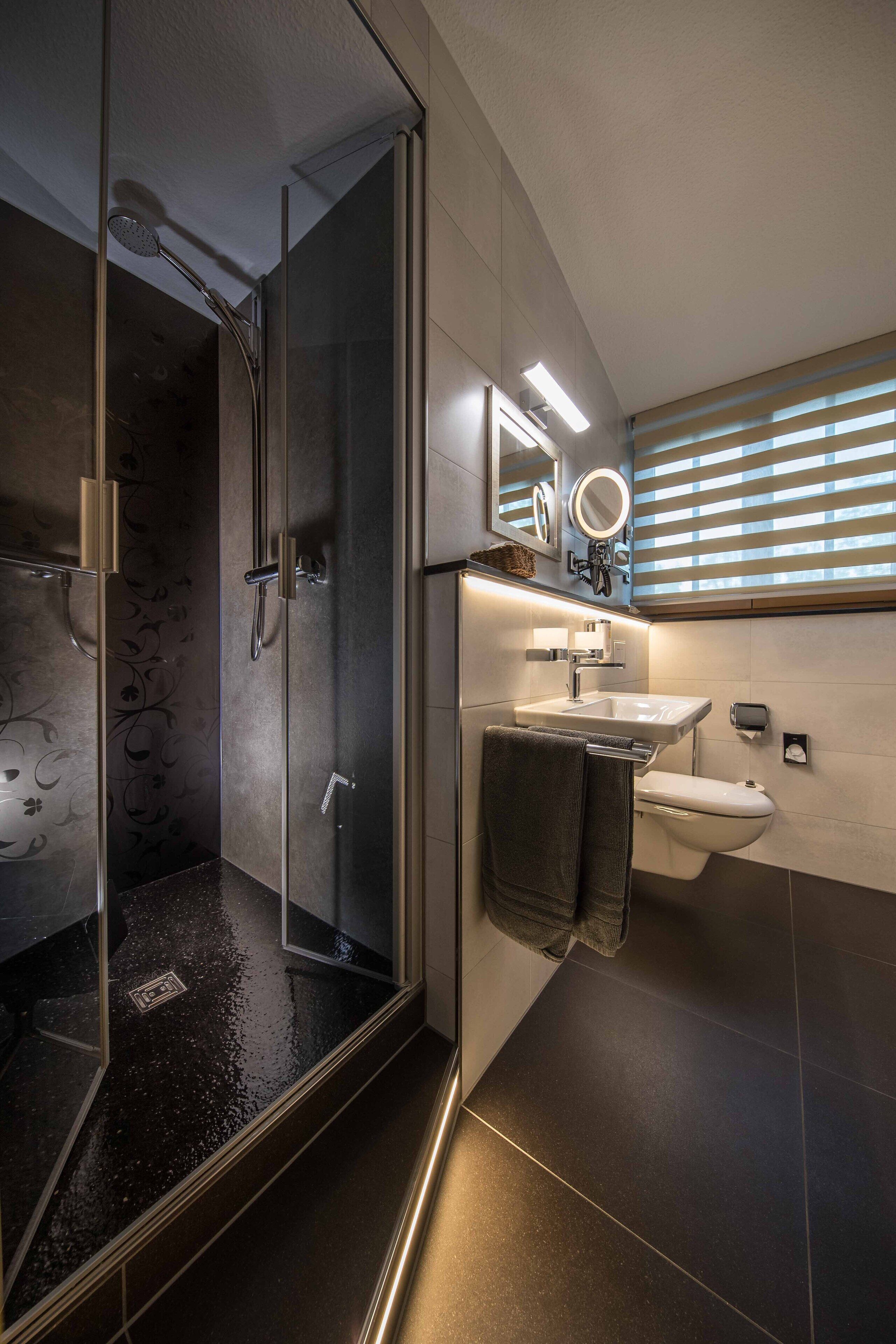 Een moderne badkamer met een douchecabine van glas, een wastafel en een toilet.