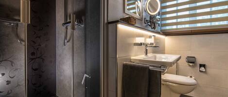 Een moderne badkamer met een douchecabine van glas, een wastafel en een toilet.