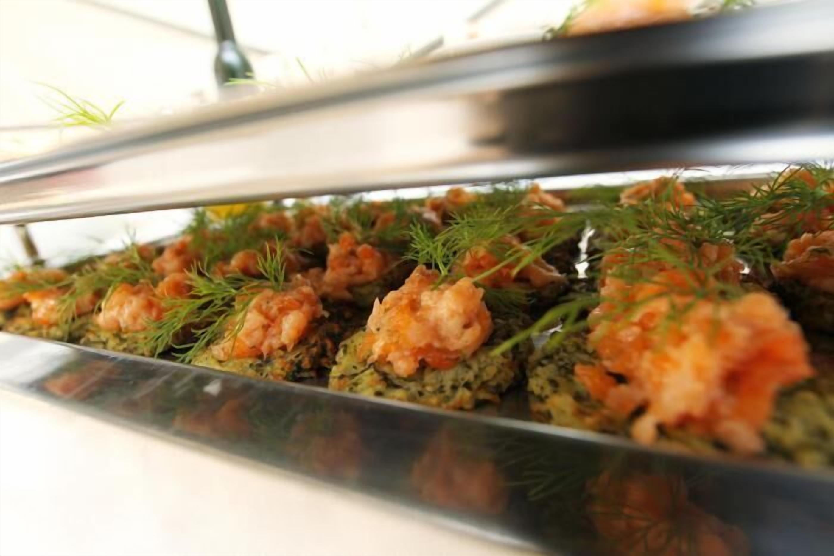 A buffet with seafood appetizers garnished with dill.