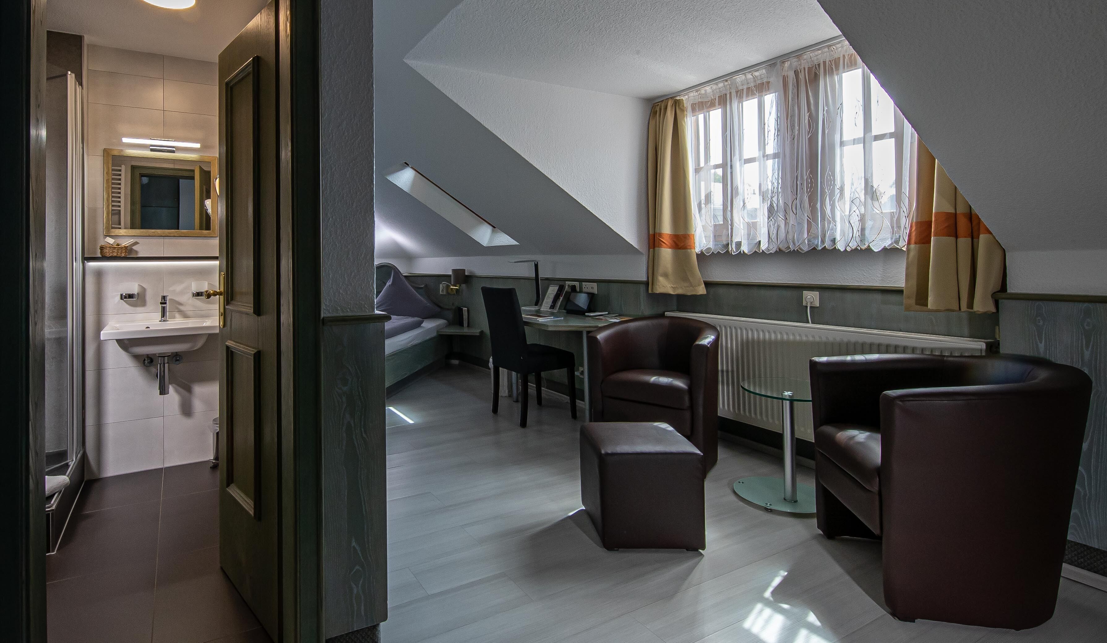 A modern, compact living space with a kitchenette, a dining area with a table and chairs, and a large window with curtains.