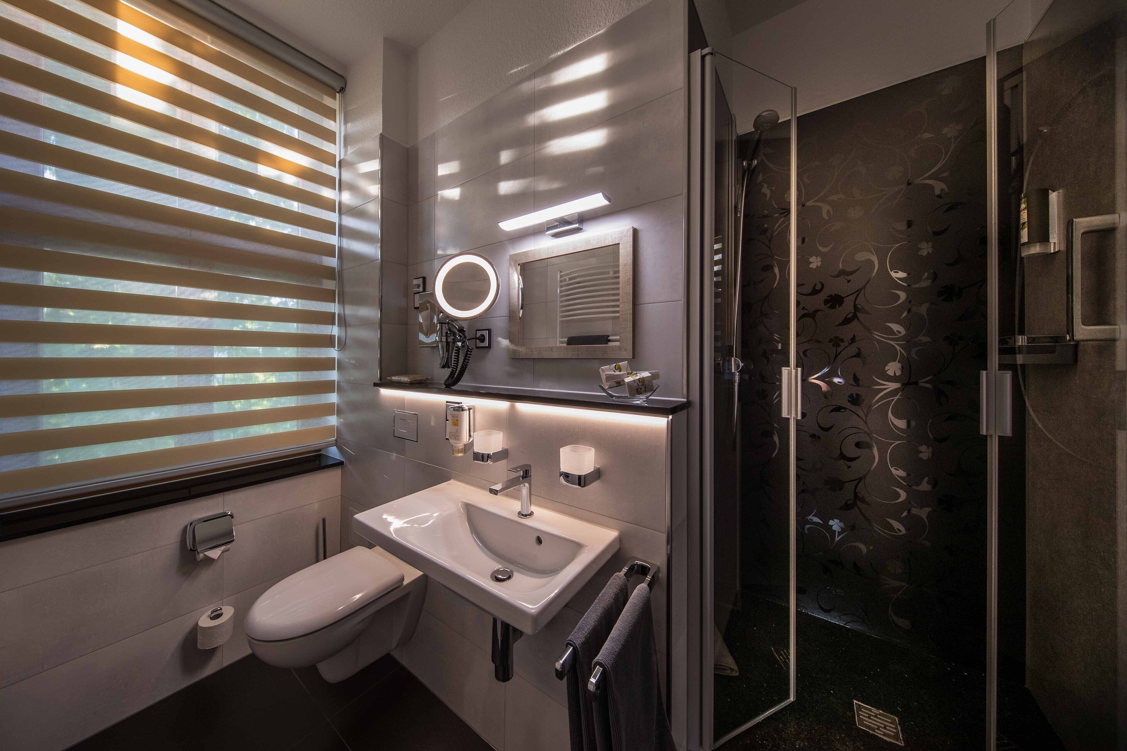 Un baño moderno con inodoro, lavamanos y ducha.