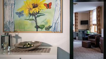 A room with a dining area, a TV mounted on the wall, and a decorative painting of a sunflower.
