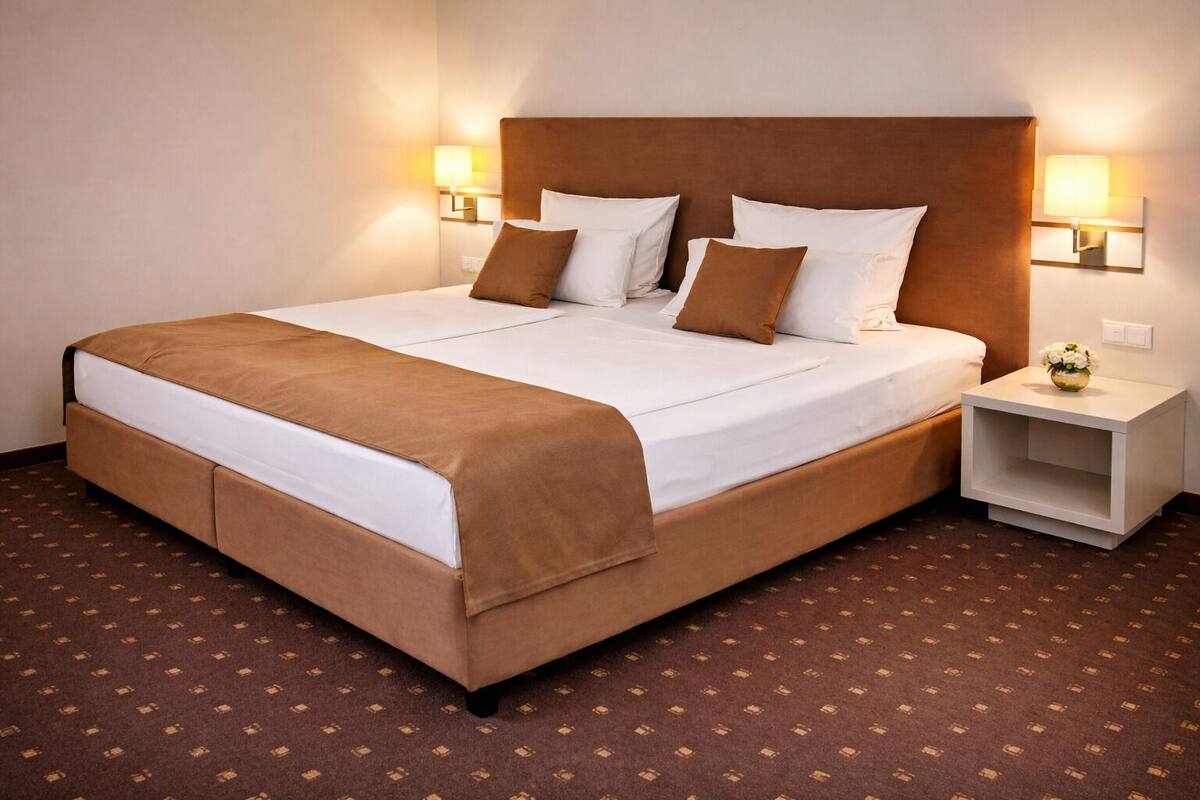 A hotel room with a large bed, two bedside tables, and a carpeted floor.