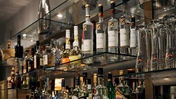 Zona de bar con estantes llenos de botellas de licores y vasos.