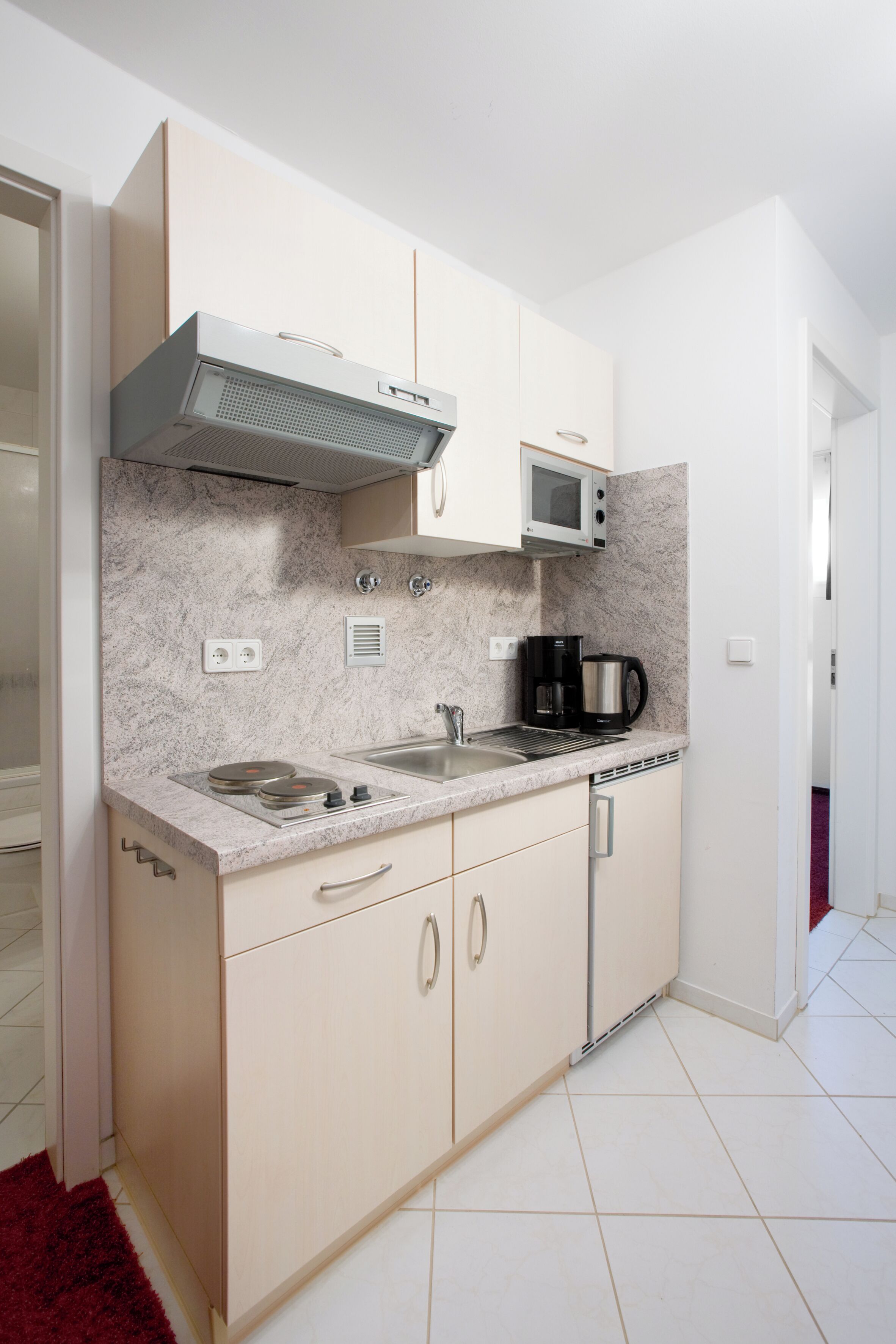 A compact kitchen with a microwave, stove, and coffee maker.