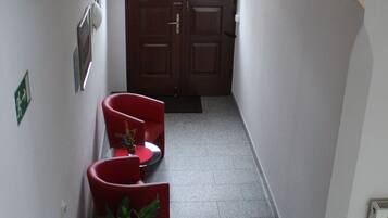A hallway with a red chair, a potted plant, and a door at the end.