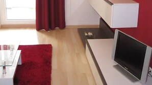 Et moderne værelse med rødt tæppe, et fladskærms-tv og et hvidt skrivebord.