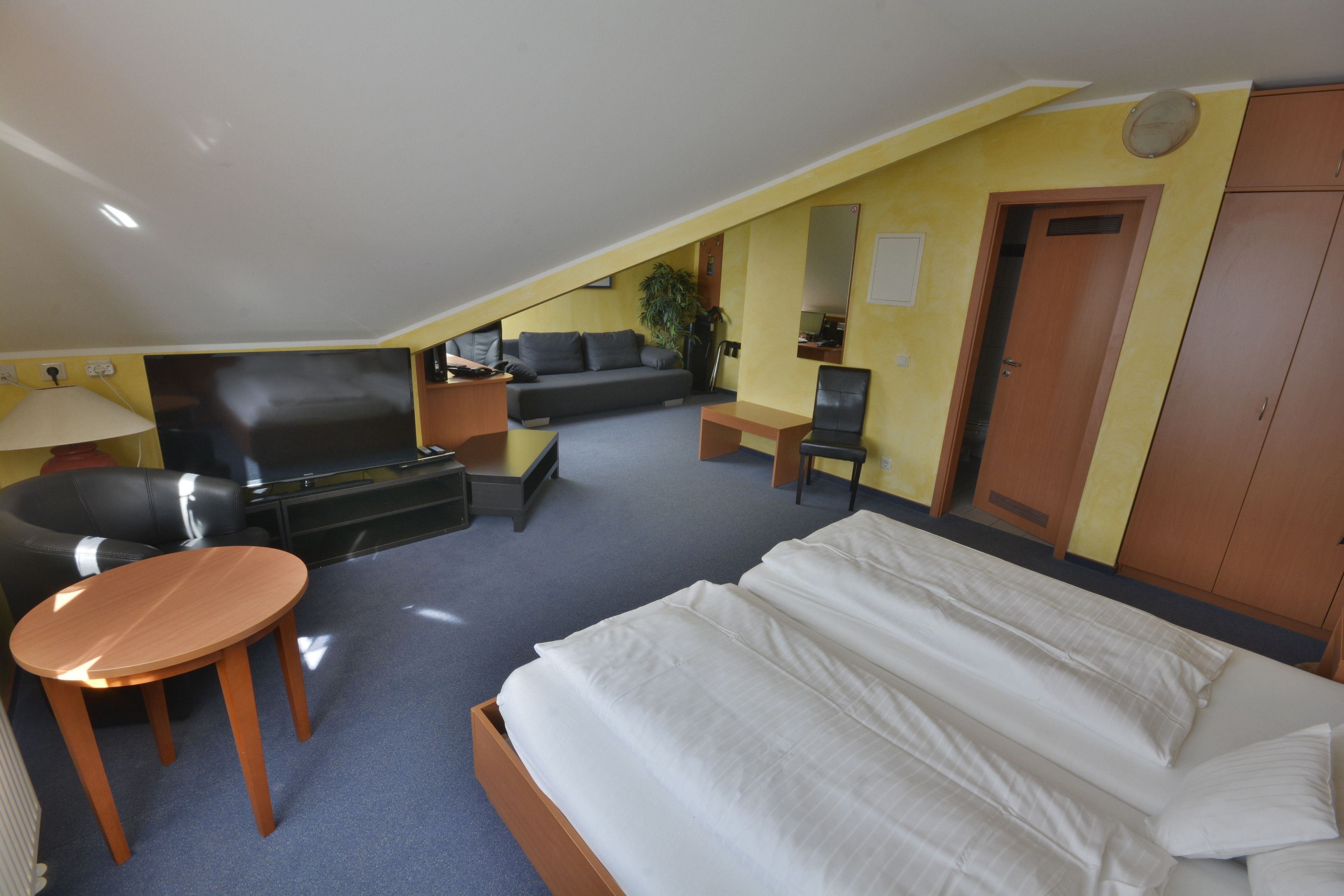 Une chambre d’hôtel avec un lit, un bureau, un canapé et une télévision.