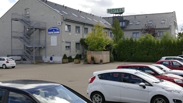 Un hotel con un letrero que dice “HOTEL NORD” y una escalera que lleva a un nivel superior. Varios coches aparcados en primer plano.