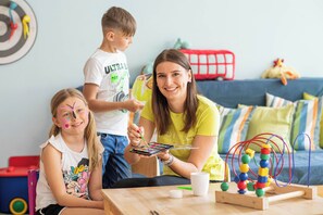 A room with a wooden table, a colorful mobile, and a red toy bus in the background.
