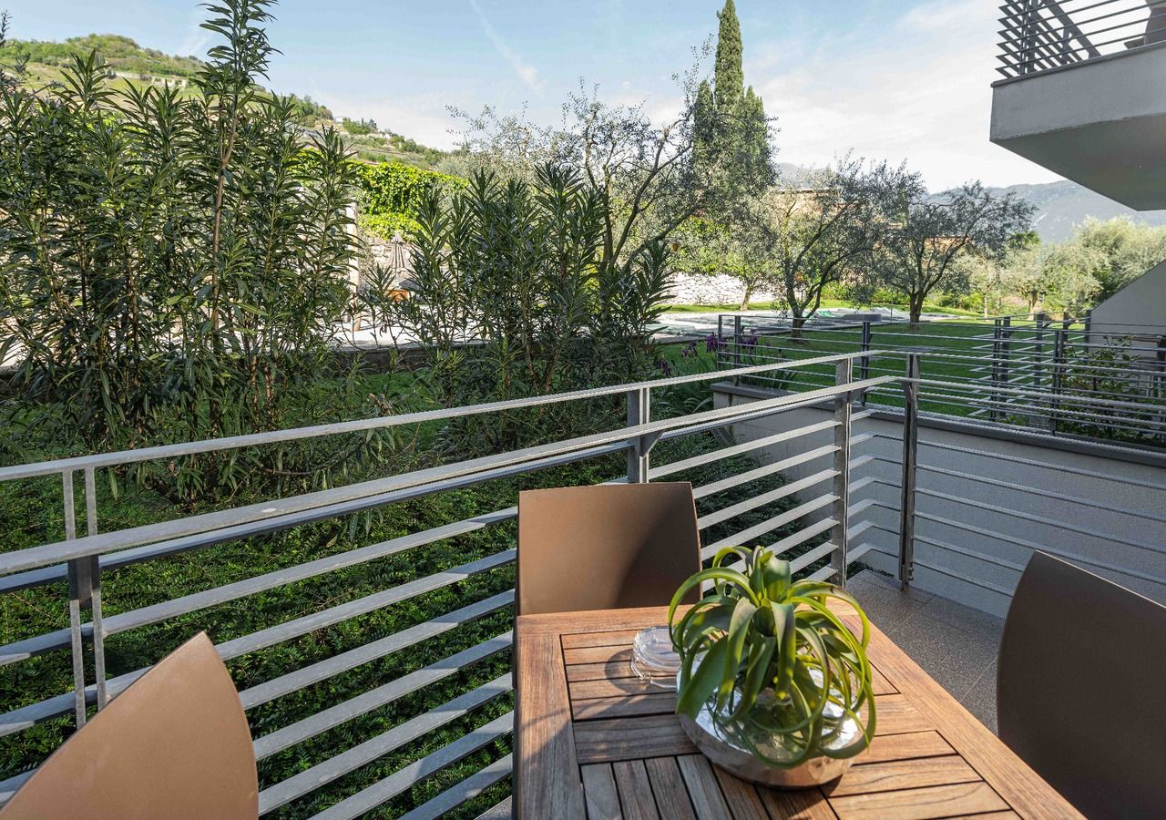 A balcony with a table, chairs, and a potted plant.