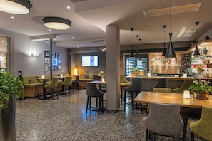 A modern interior with a bar area, seating arrangements, and a projection screen.